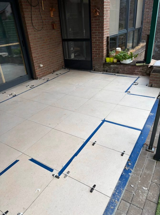 Grote keramische terrastegels, uitgelijnd met tape en tegelclips